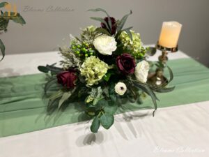 Plum Floral Arrangement by Blooms Collection: A captivating fusion of roses, berries, hydrangeas, eucalyptus, and greens. Versatile centerpiece or aisle decoration, perfect for weddings or special events. Premium artificial flowers ensure lifelike allure.
