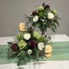 Plum Floral Arrangement by Blooms Collection: A captivating fusion of roses, berries, hydrangeas, eucalyptus, and greens. Versatile centerpiece or aisle decoration, perfect for weddings or special events. Premium artificial flowers ensure lifelike allure.