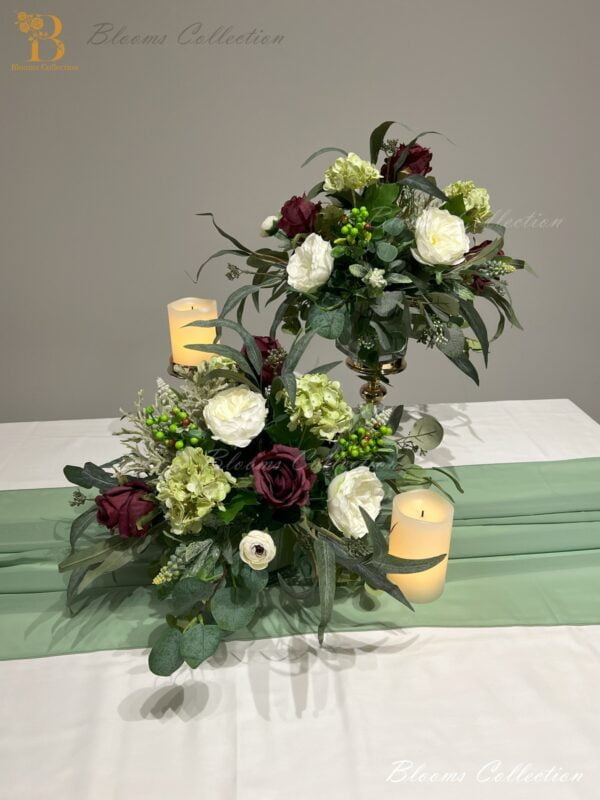 Plum Floral Arrangement by Blooms Collection: A captivating fusion of roses, berries, hydrangeas, eucalyptus, and greens. Versatile centerpiece or aisle decoration, perfect for weddings or special events. Premium artificial flowers ensure lifelike allure.