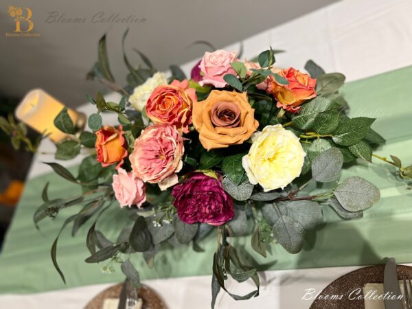 Stunning Floral Arrangement by Blooms Collection: Vibrant magenta, yellow, orange, and pink tones with roses, peonies, eucalyptus, and rose leaves. Ideal for weddings, corporate events, birthdays, and evening functions.