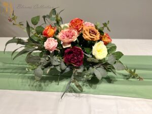 Stunning Floral Arrangement by Blooms Collection: Vibrant magenta, yellow, orange, and pink tones with roses, peonies, eucalyptus, and rose leaves. Ideal for weddings, corporate events, birthdays, and evening functions.